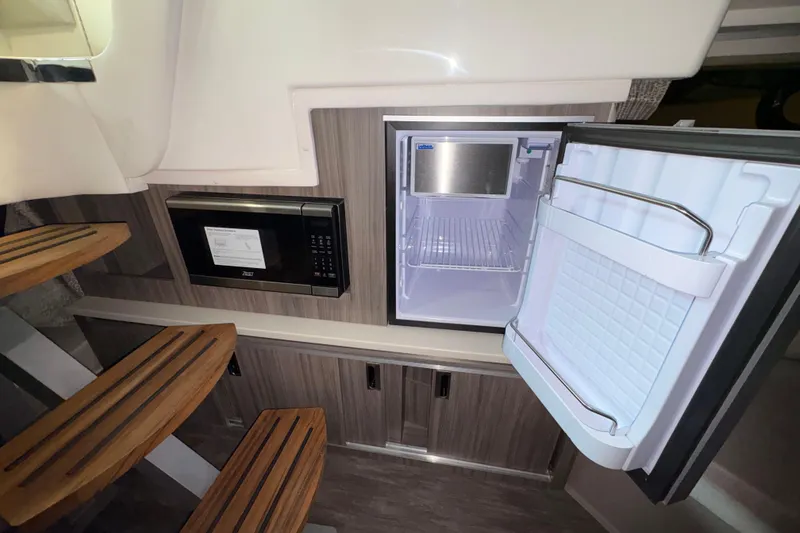 Slide: The Image of Interior of 2026 Sea Ray Sundancer 320 with open fridge and microwave. - 9