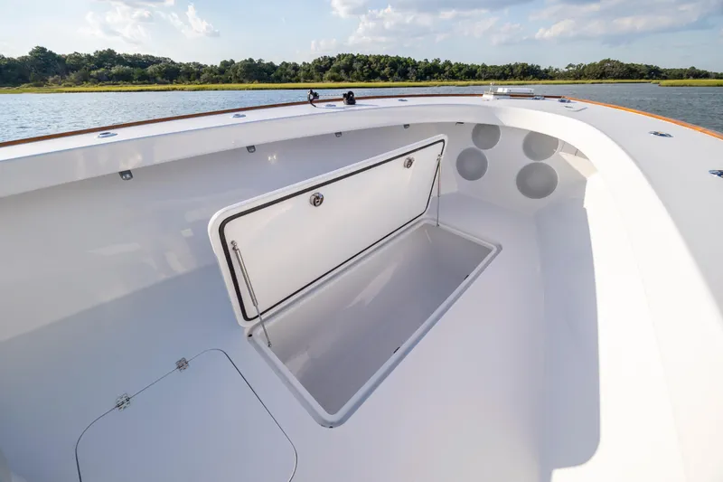 Slide: The Image of Open storage compartment on 2018 Tribute 37 boat, with scenic water and forest backdrop. - 16
