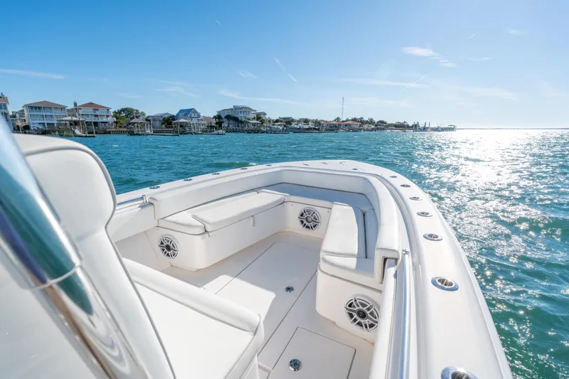Slide: The Image of 2023 Contender 28 Sport boat cruising on sunny waters near coastal homes. - 4