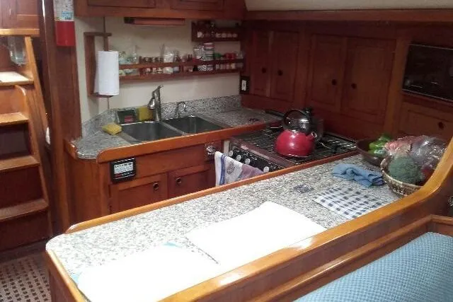 Slide: The Image of 1980 Nordic 44 yacht kitchen with wooden cabinets, granite countertops, and a stainless steel sink. - 2