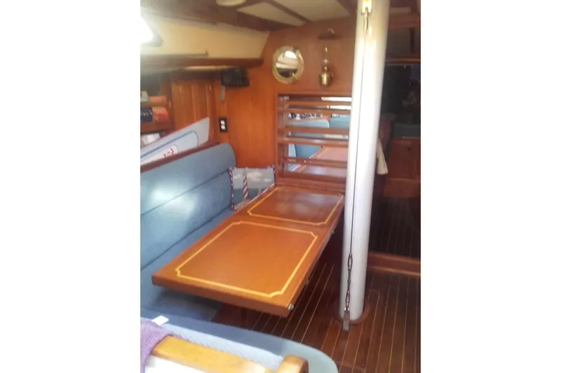 Slide: The Image of Interior of 1980 Nordic 44 sailboat with wooden table and blue seating. - 4