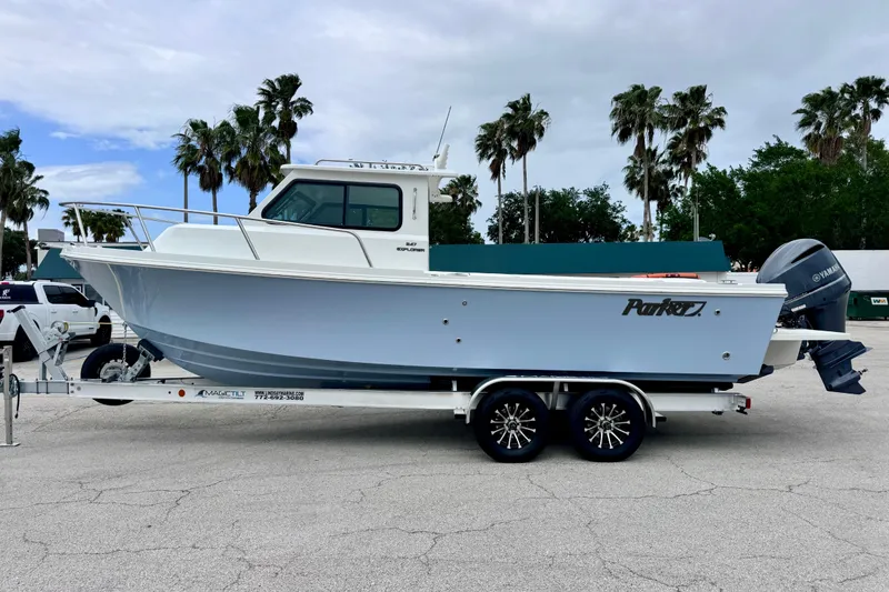 Slide: The Image of 2026 Parker 247 Explorer boat on trailer, parked outdoors with palm trees in background. - 2