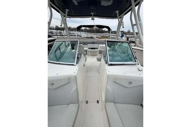 Slide: The Image of 2019 Striper 230 DC boat interior with dual consoles and seating, docked by the water. - 15