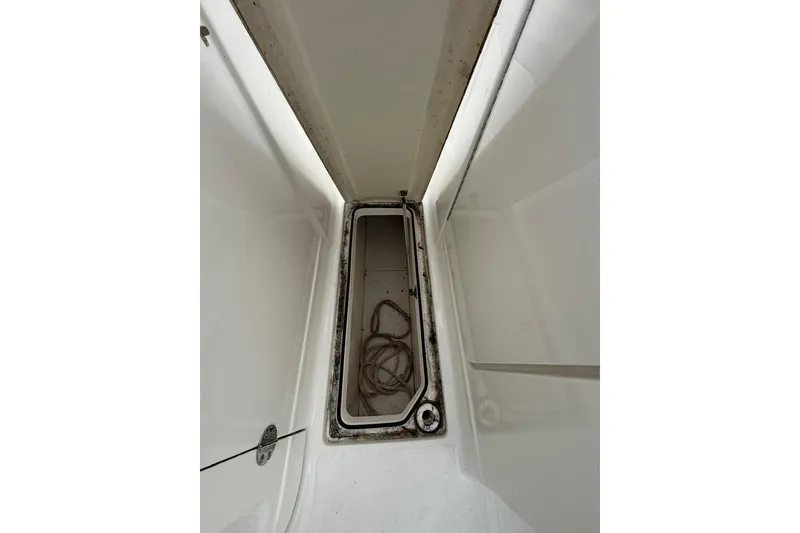 Slide: The Image of Storage compartment of a 2019 Striper 230 DC boat with coiled rope inside. - 32