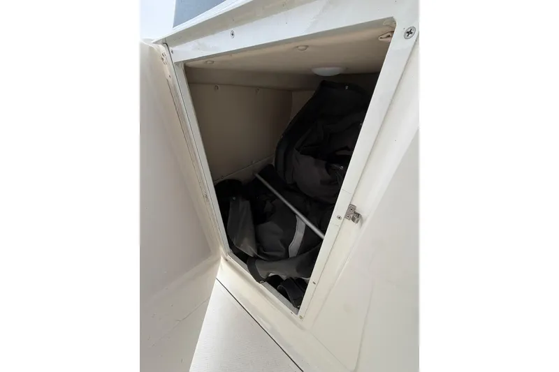 Slide: The Image of Open storage compartment on 2019 Striper 230 DC boat, containing black gear. - 33