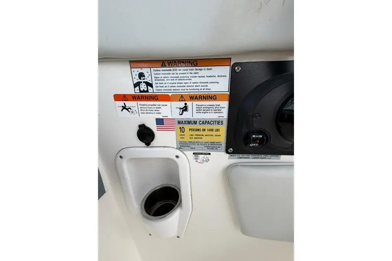 Slide: The Image of Warning labels and capacity information on a 2019 Striper 230 DC boat dashboard. - 35