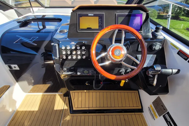 Slide: The Image of 2023 NX Boats NX340 helm with wooden steering wheel and modern controls. - 14
