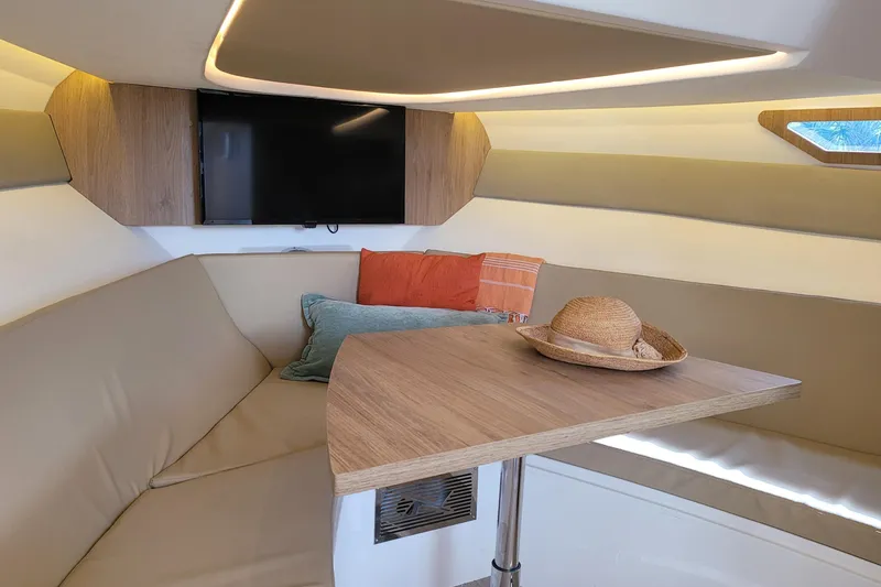 Slide: The Image of Interior of 2023 NX Boats NX340 with cozy seating, table, and TV. - 17