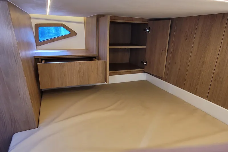 Slide: The Image of 2023 NX Boats NX340 cabin interior with wooden storage and window. - 22