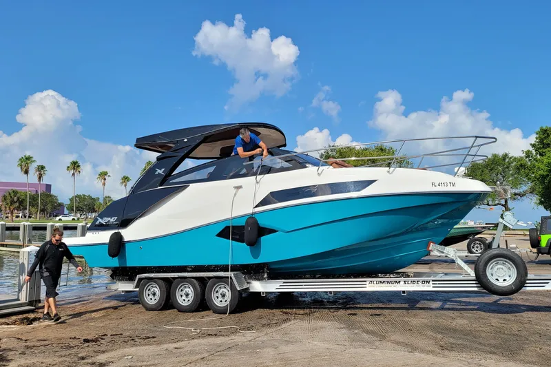 Slide: The Image of 2023 NX Boats NX340 on trailer, vibrant blue and white design, sunny day backdrop. - 3