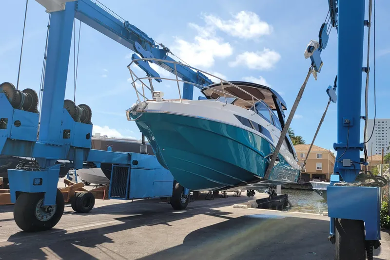 Slide: The Image of 2023 NX Boats NX340 being lifted by a blue crane at a marina. - 5