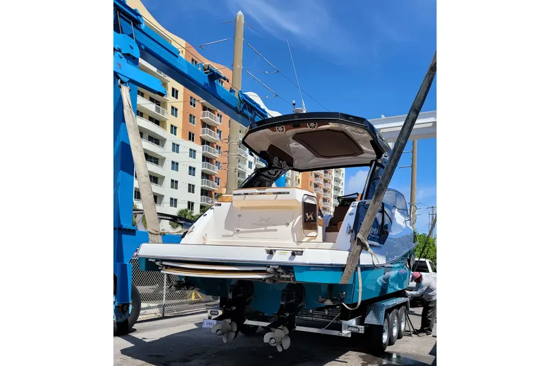 Slide: The Image of 2023 NX Boats NX340 on trailer, vibrant blue hull, urban backdrop, sunny day. - 6