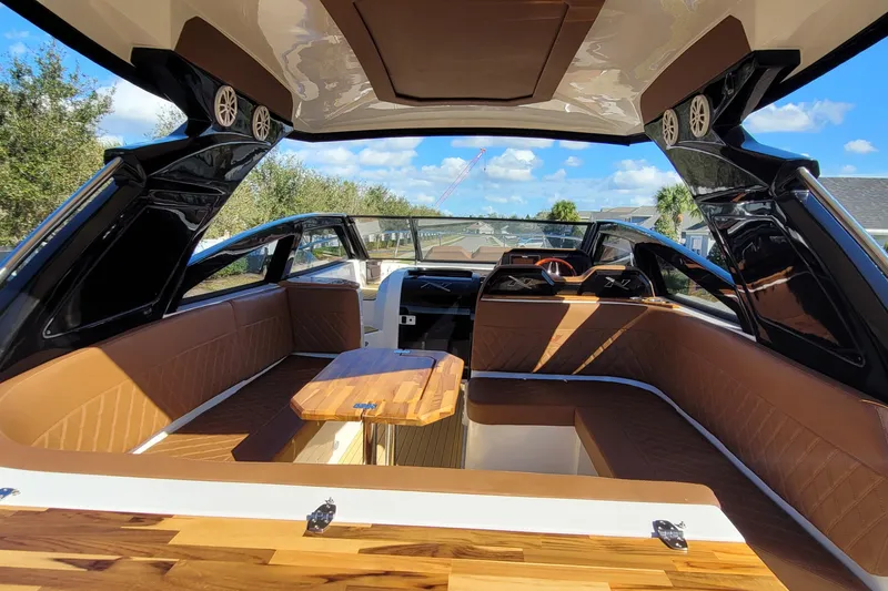 Slide: The Image of Interior of 2023 NX Boats NX340, featuring luxurious seating and wooden table under a sunny sky. - 8