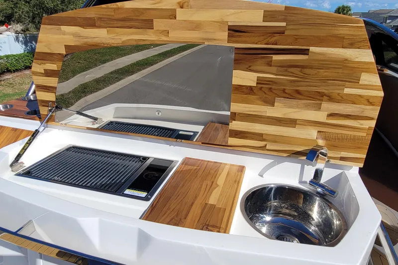Slide: The Image of 2023 NX Boats NX340 kitchen area with wooden paneling, grill, and sink. - 9