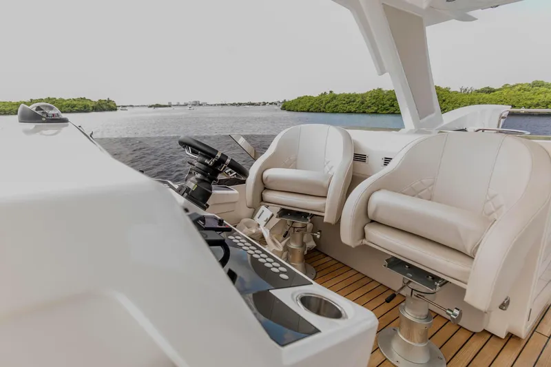 Slide: The Image of Luxury helm seating on 2021 Sunseeker Manhattan 68 yacht, overlooking serene waters. - 67