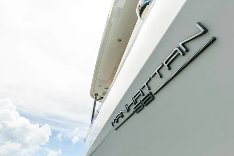 Slide: The Image of 2021 Sunseeker Manhattan 68 yacht exterior with logo against a cloudy sky. - 78