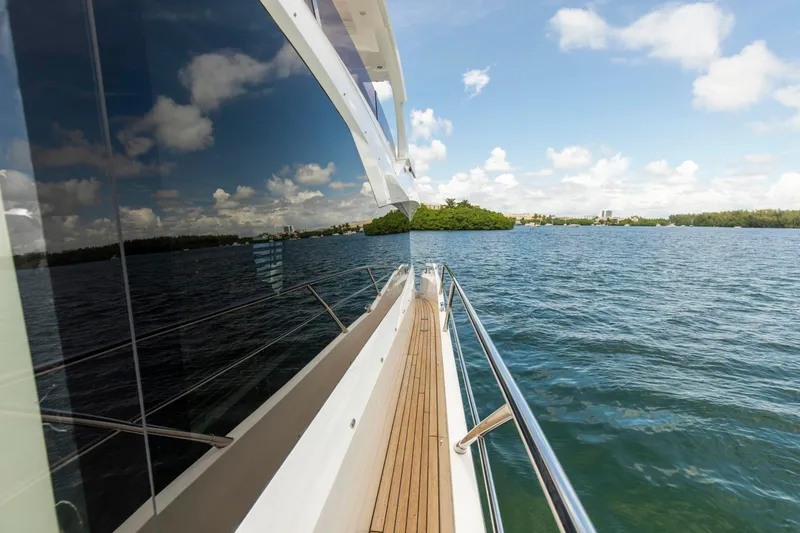 Slide: The Image of 2021 Sunseeker Manhattan 68 yacht cruising on a sunny day, reflecting blue skies and clouds. - 91