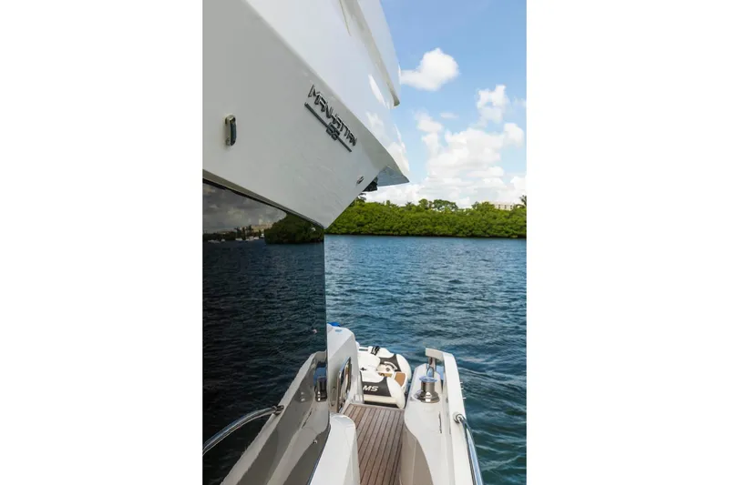 Slide: The Image of Sunseeker Manhattan 68 yacht, 2021 model, docked by serene waters under a clear sky. - 94