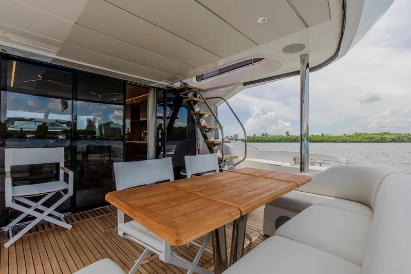 Slide: The Image of Outdoor seating area on 2021 Sunseeker Manhattan 68 yacht, featuring wooden table and scenic water view. - 99