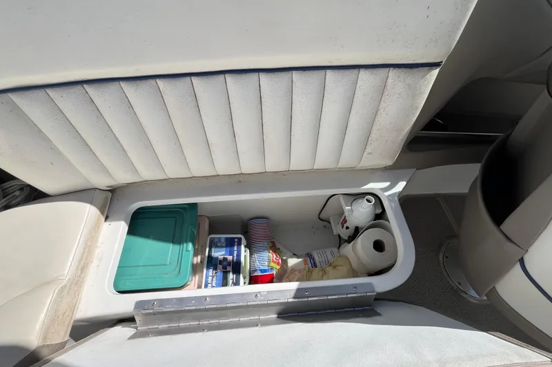 Slide: The Image of Storage compartment in a 2006 Cobalt 272 boat with various items, including containers and paper towels. - 30