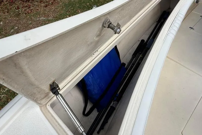 Slide: The Image of Open storage compartment on a 2003 Intrepid 289 Center Console boat, containing fishing rods and gear. - 37