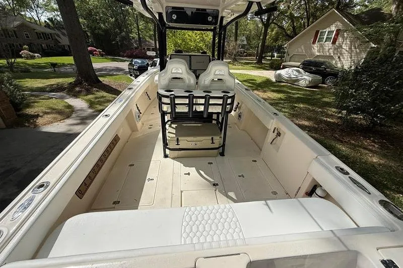 Slide: The Image of 2003 Intrepid 289 Center Console boat interior with seating and console, parked in a residential driveway. - 8
