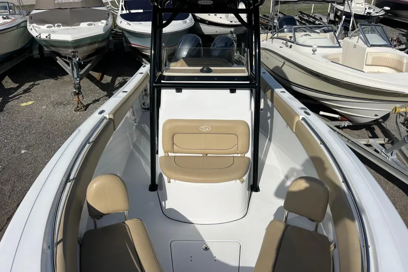 Slide: The Image of 2017 Sportsman Heritage 251 Center Console boat with beige seating, docked among other boats. - 10
