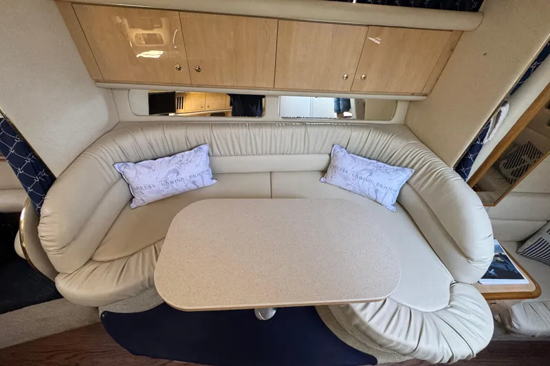 Slide: The Image of 2001 Sea Ray 340 Sundancer cabin with beige seating and table, featuring decorative pillows. - 29