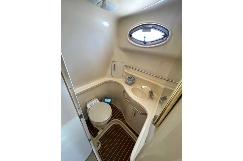 Slide: The Image of 2001 Sea Ray 340 Sundancer bathroom with toilet, sink, and porthole window. - 32