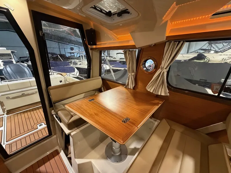 Slide: The Image of Interior of 2023 Ranger Tugs R 25 NW with wooden table and seating area. - 7