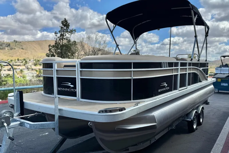 Slide: The Image of 2022 Bennington SX23 Salt Water Series pontoon boat on trailer under cloudy sky. - 3