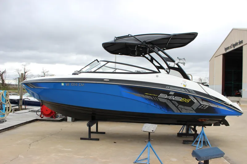 Slide: The Image of 2017 Yamaha Boats 242 Limited S E-Series in blue, docked on a stand. - 2