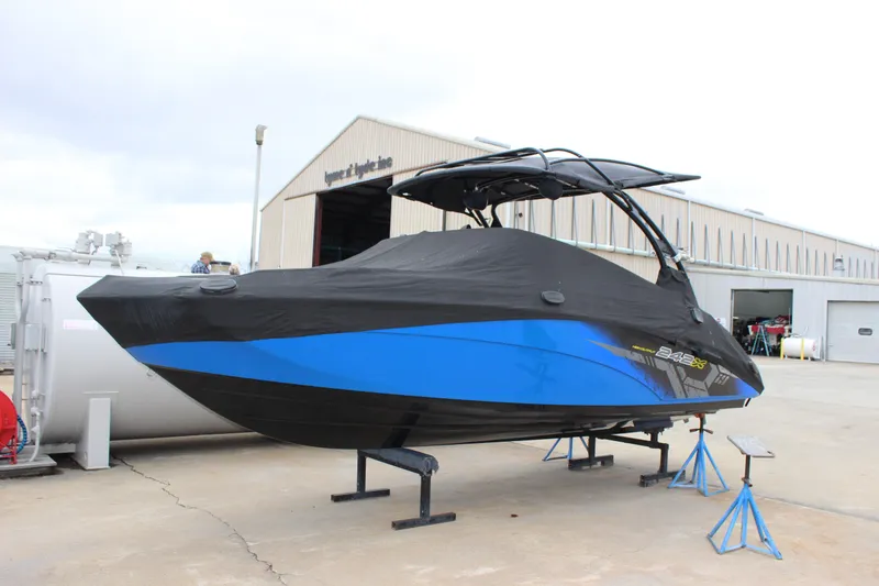 Slide: The Image of 2017 Yamaha Boats 242 Limited S E-Series covered, displayed on stands outside a warehouse. - 7