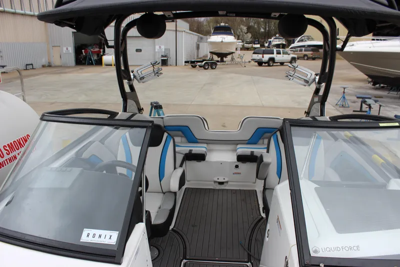 Slide: The Image of 2017 Yamaha Boats 242 Limited S E-Series interior with blue and white seating, docked at marina. - 8