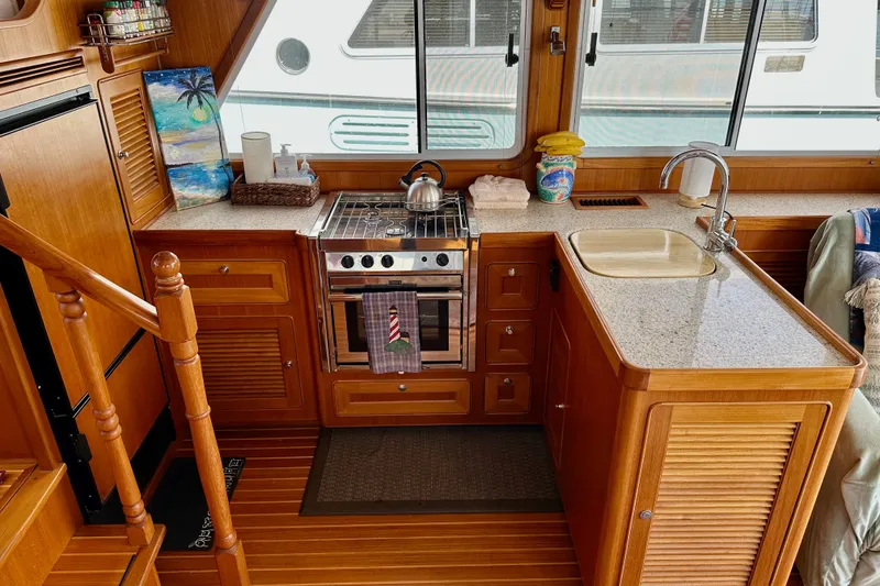 Slide: The Image of Helmsman Trawlers 38 Pilothouse 2016 kitchen with stove, sink, and wooden cabinetry. - 12