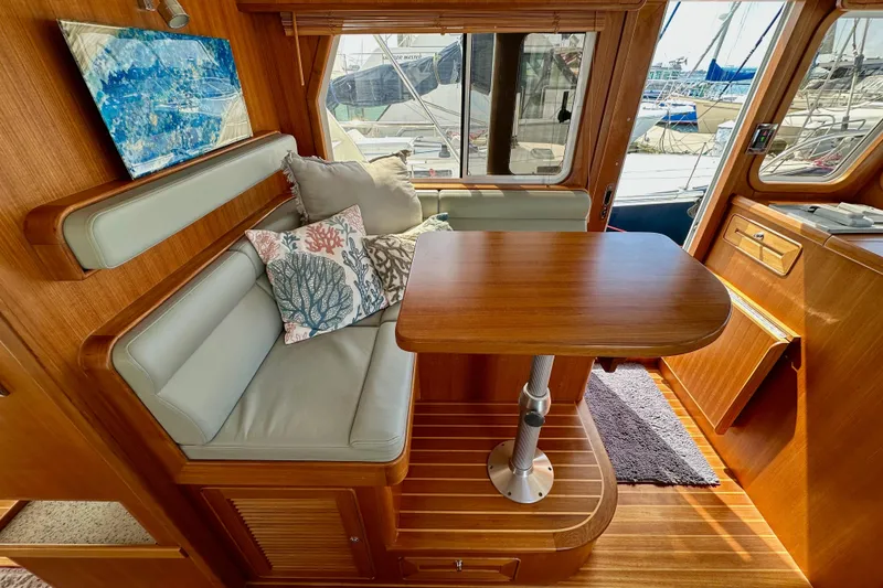 Slide: The Image of 2016 Helmsman Trawlers 38 Pilothouse interior with cozy seating and wooden table. - 16