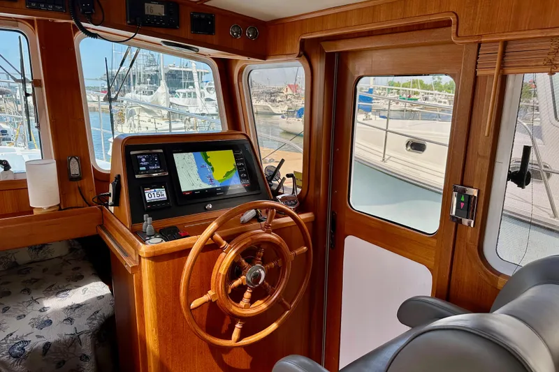 Slide: The Image of 2016 Helmsman Trawlers 38 Pilothouse interior with navigation equipment and wooden steering wheel. - 18