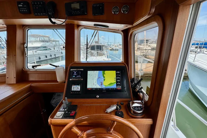 Slide: The Image of 2016 Helmsman Trawlers 38 Pilothouse interior with navigation equipment and marina view. - 20