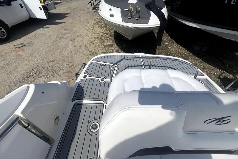 Slide: The Image of 2011 Monterey 254FSC boat with sleek white seating and gray deck, parked outdoors. - 10