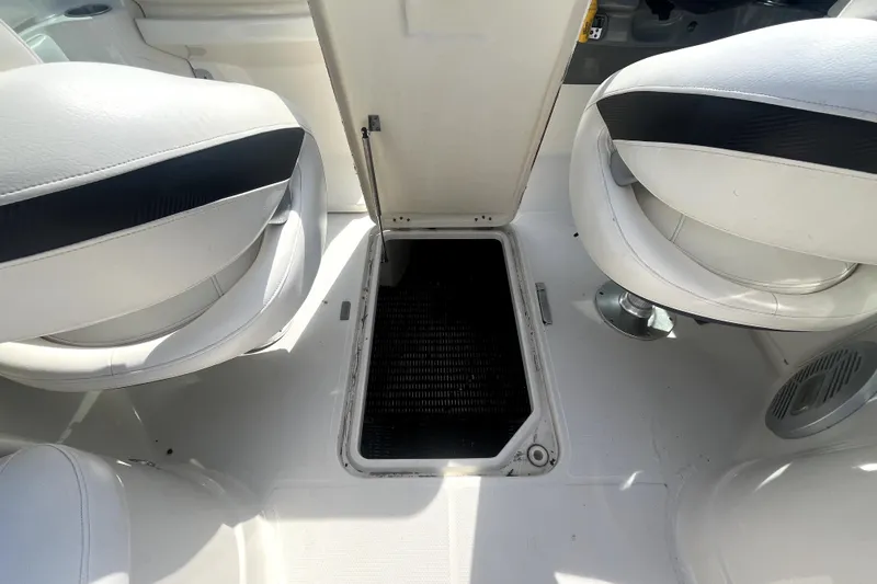 Slide: The Image of 2011 Monterey 254FSC boat interior with open storage compartment between white seats. - 22