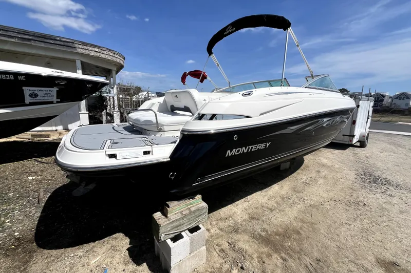 Slide: The Image of 2011 Monterey 254FSC boat on trailer, white and black exterior, sunny day. - 5