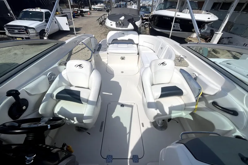 Slide: The Image of 2011 Monterey 254FSC boat interior with white seating and steering wheel, docked near other boats. - 20