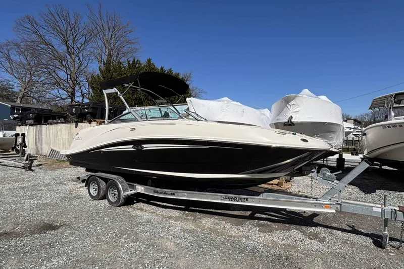 The Image of 2008 Sea Ray 260 Sundeck boat on trailer, parked outdoors under clear blue sky. - 0