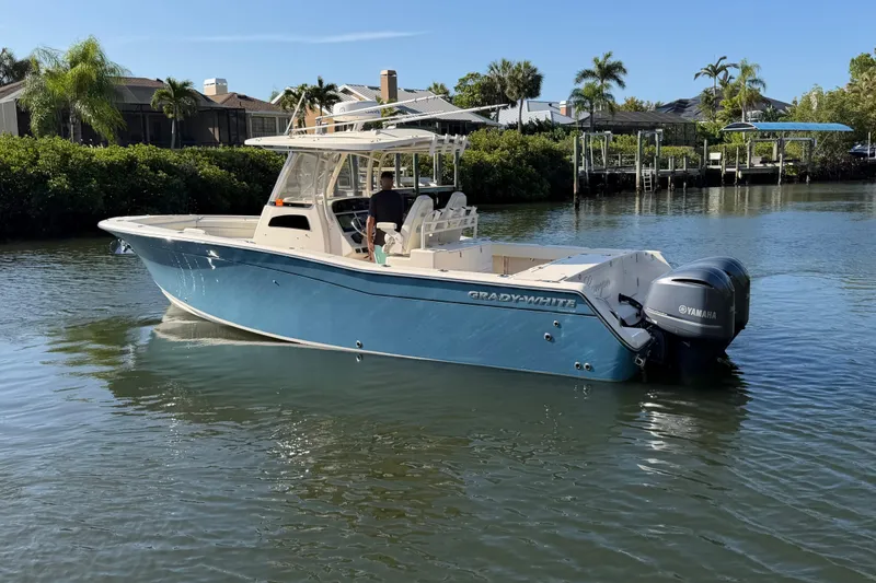 The Image of 2018 Grady-White Canyon 306 boat on calm water, surrounded by lush greenery. - 0