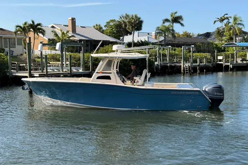 Slide: The Image of 2018 Grady-White Canyon 306 boat cruising on a sunny waterfront with palm trees. - 1