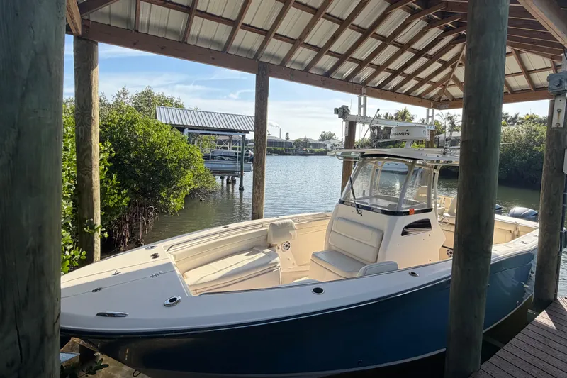 Slide: The Image of 2018 Grady-White Canyon 306 boat docked under a wooden shelter by the water. - 10