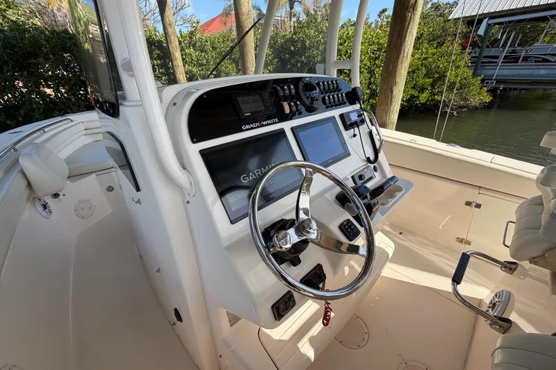Slide: The Image of 2018 Grady-White Canyon 306 boat cockpit with steering wheel and navigation controls. - 26
