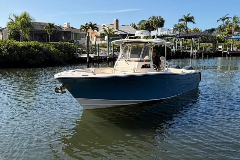 Slide: The Image of 2018 Grady-White Canyon 306 boat cruising on a sunny waterfront with palm trees. - 9