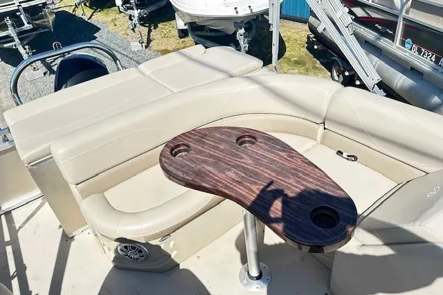 Slide: The Image of 2016 Avalon LSV Tri Toon boat interior with beige seating and wooden table. - 8