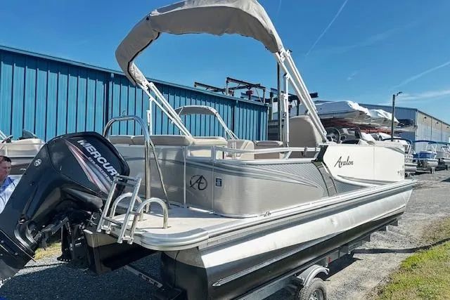 Slide: The Image of 2016 Avalon LSV Tri Toon pontoon boat with Mercury outboard motor, parked outdoors. - 2